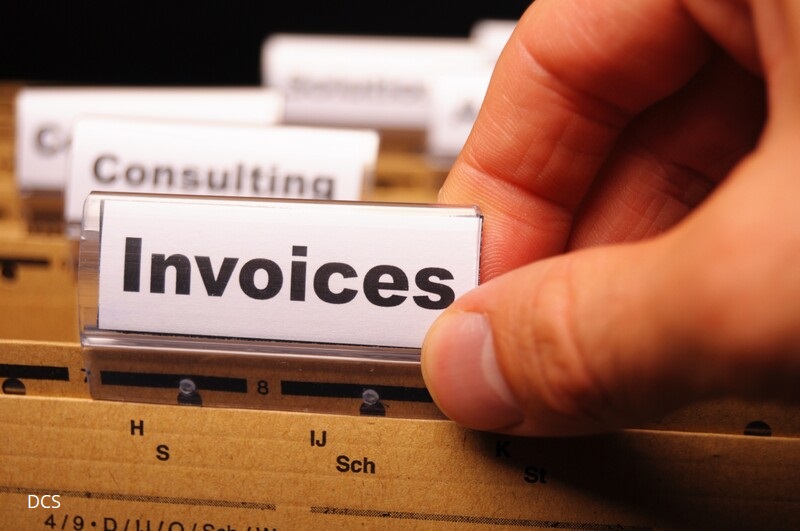 Image showing folders in a filing cabinet with fingers on a tab marked INVOICES